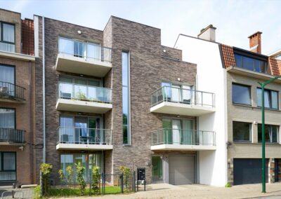 Façade d'un immeuble à appartements finalisé par Dawo Group, en briques grises avec balcons en verre