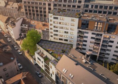 Vue aérienne du projet Palais à Schaerbeek : immeuble blanc avec toiture végétalisée, panneaux solaires et terrasse